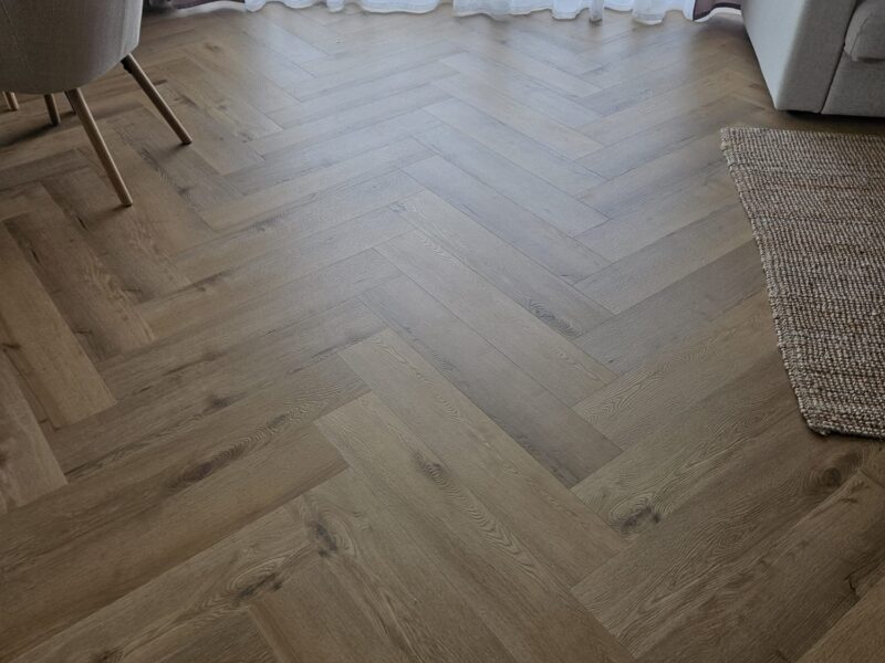 Salon z drewnianą podłogą jodełkową , realizacja Varia
